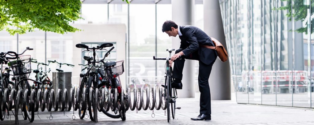 A buinessman takes his bicycle off the bike rack outside an office building